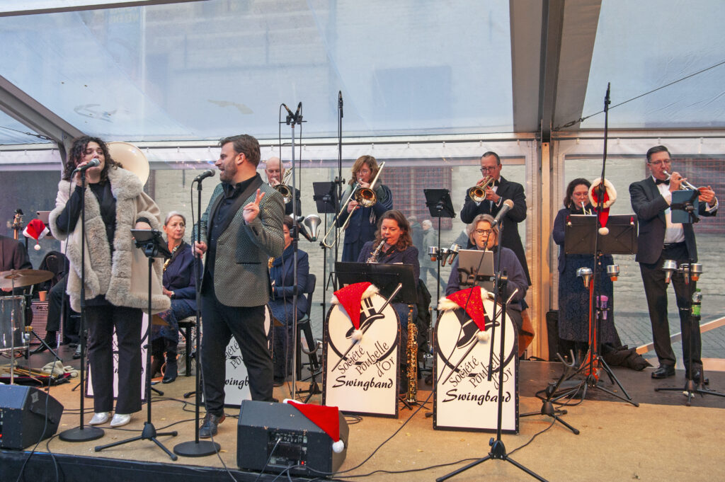 Band speelt live jazzmuziek op een podium in een overdekte ruimte met zangers en blazerssectie in stijlvolle kleding liveoptreden boeiende muziek en energieke sfeer.